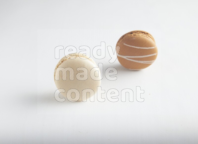 45º Shot of of two assorted Brown Irish Cream, and White Caramel fleur de sel macarons on white background