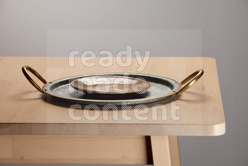 multicolored plate placed on a rounded stainless steel tray with golden handels on the edge of wooden table