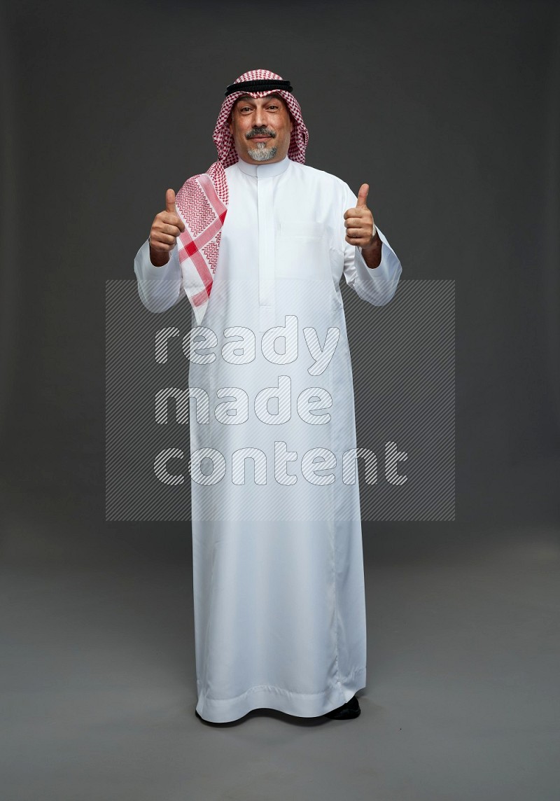 Saudi man with shomag Standing Interacting with the camera on gray background