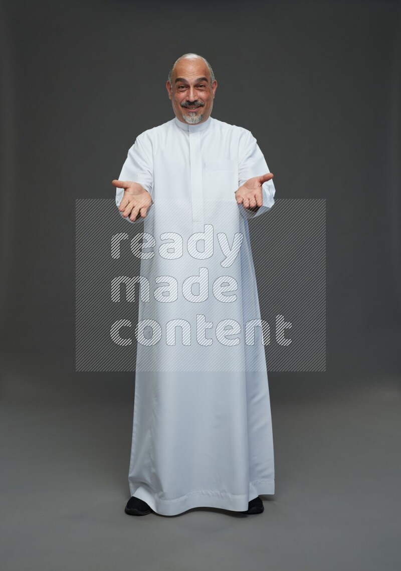 Saudi man without shomag Standing Interacting with the camera on gray background