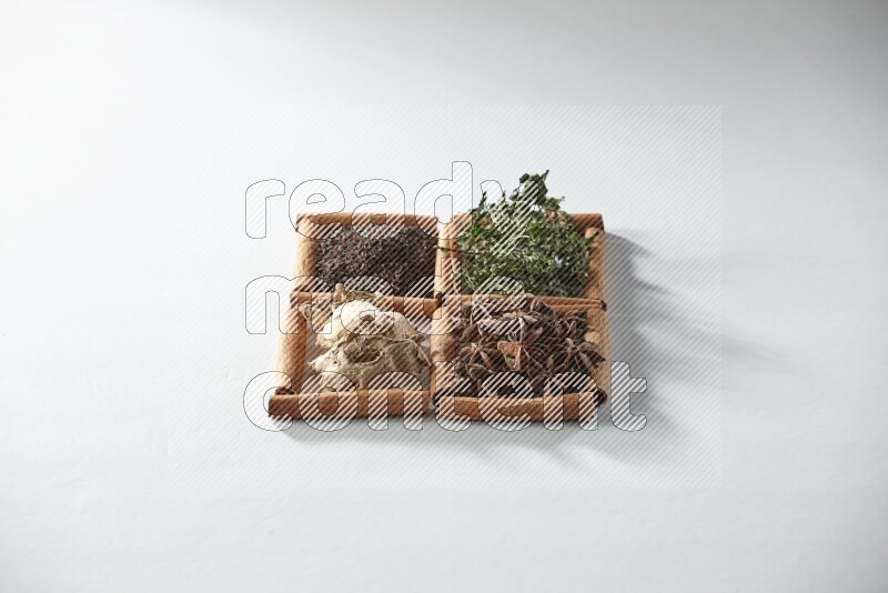 4 مربعات من أعواد القرفة ممتلئة بالشاي والنعناع واليانسون والزنجبيل على أرضية بيضاء