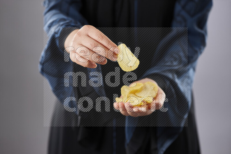 Woman in abaya holding different kinds of snacks in different positions