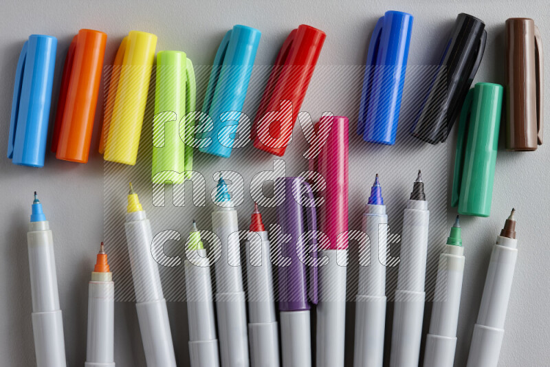 An arrangement of coloring pens in different colors on grey background