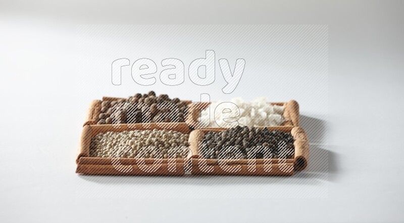 4 squares of cinnamon sticks full of allspice, white salt, white pepper and black pepper on white flooring