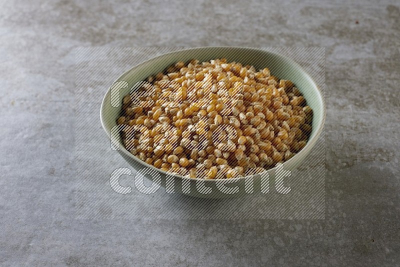 corn kernel in a green ceramic bowl on a grey textured countertop