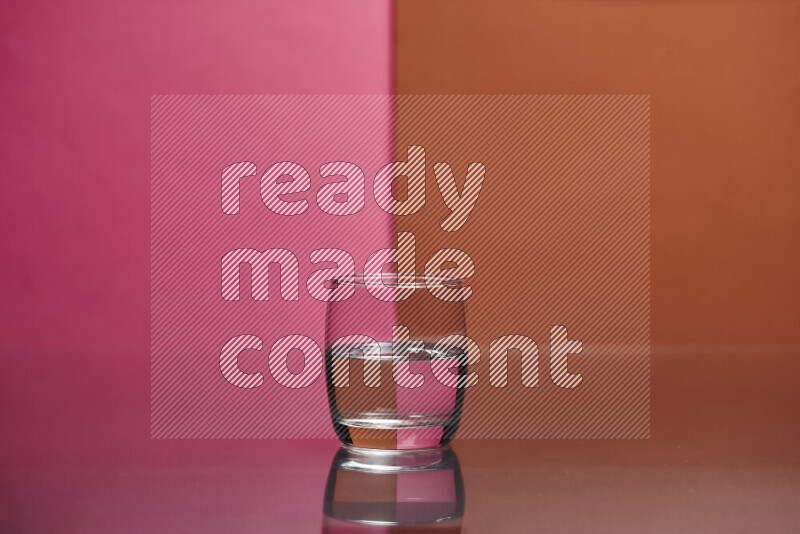 The image features a clear glassware filled with water, set against pink and dark orange background