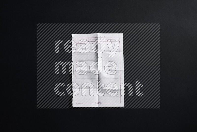 Folded notebook sheet on black background