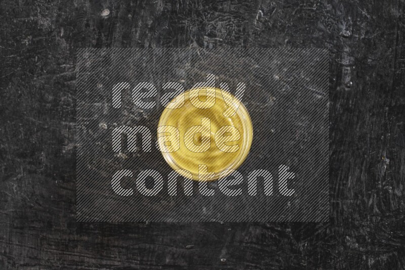 وعاء زجاجي ممتلئ بمعجون الخردل على خلفية سوداء