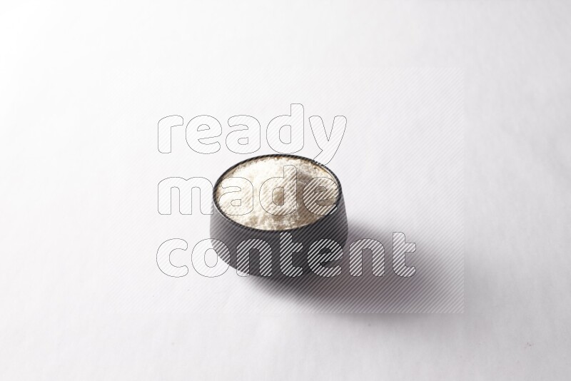 جوز هند مجفف في وعاء فخار أسود على خلفية بيضاء