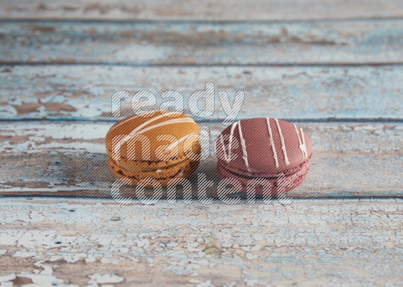 45º Shot of of two assorted Brown Irish Cream, and Red Poppy Flower macarons  on light blue background