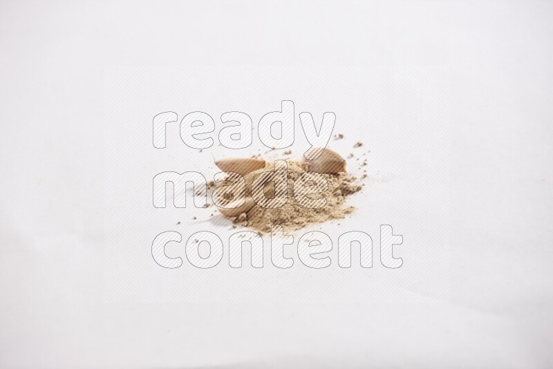 A small pile of garlic powder with some of cloves and a whole garlic bulb on a white flooring
