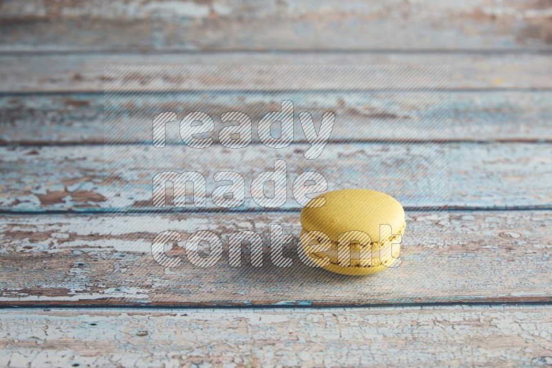 45º Shot of Yellow Lime macaron on light blue wooden background