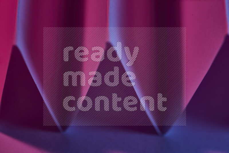 صورة مجردة مقربة تظهر طيات ورقية هندسية حادة بتدرجات اللون الارجواني