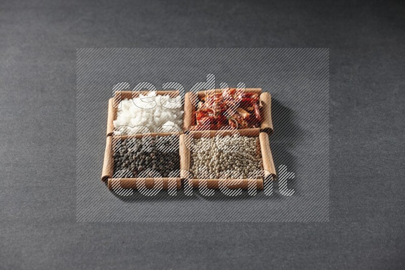 4 squares of cinnamon sticks full of black pepper, white pepper, dried red chilis and white salt on black flooring
