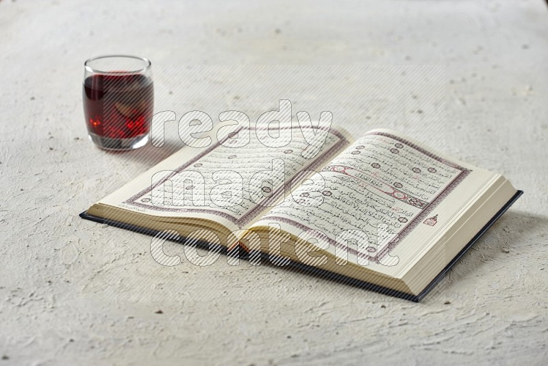 Quran with dates, prayer beads and different drinks all placed on textured white background