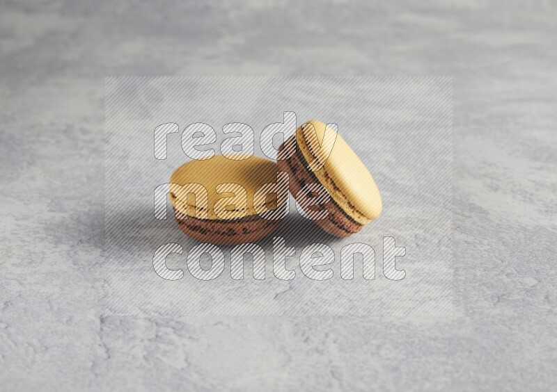 45º Shot of two Yellow and Brown Chai Latte macarons r on white  marble background