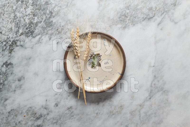 Wheat stalks on decorative pottery plate on grey marble background