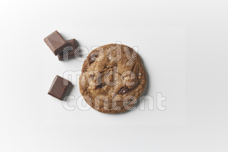 A single chocolate chips cookie with chocolate beside it on a white background