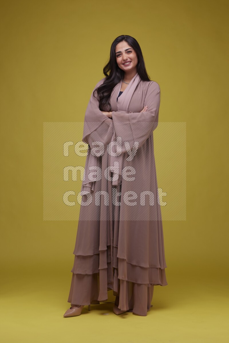 A woman Posing on a Yellow Background wearing Brown Abaya