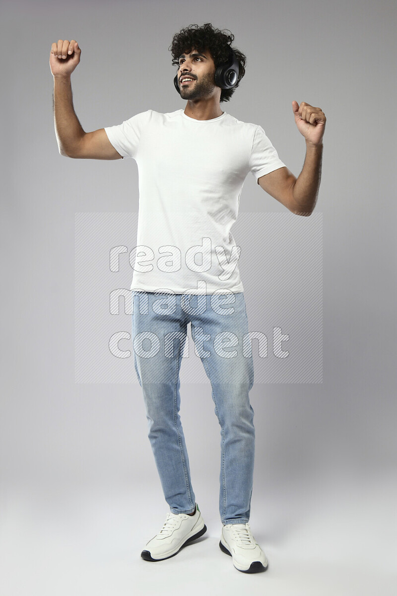 A man wearing casual standing and putting on headphones on white background