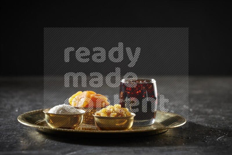 Dried fruits in metal bowls with tamarind on a tray in dark setup