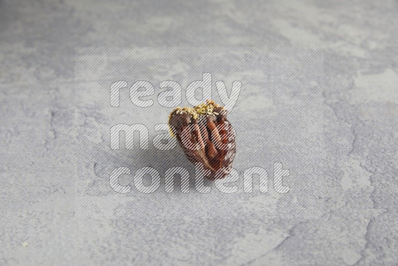 pecan stuffed date covered with Dark chocolate and chopped pistachios on alight grey background