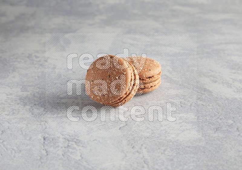 45º Shot of two Brown Hazelnuts macarons  on white  marble background