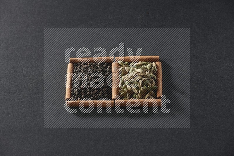 2 squares of cinnamon sticks full of black peppers and cardamom on black flooring