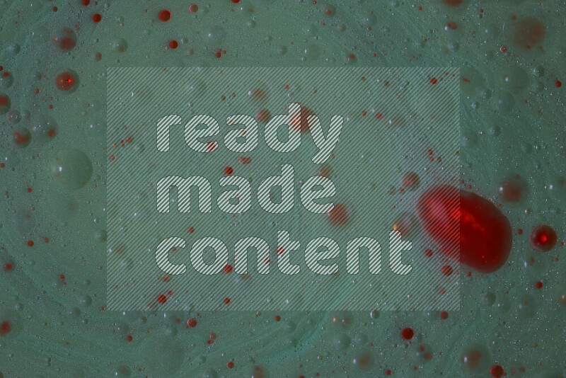 The image captures a dramatic splatter of red paint over a green backdrop