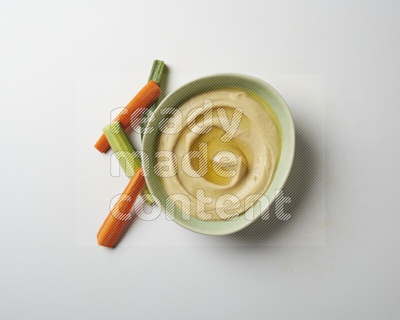 Hummus in a green plate garnished with olive oil on a white background