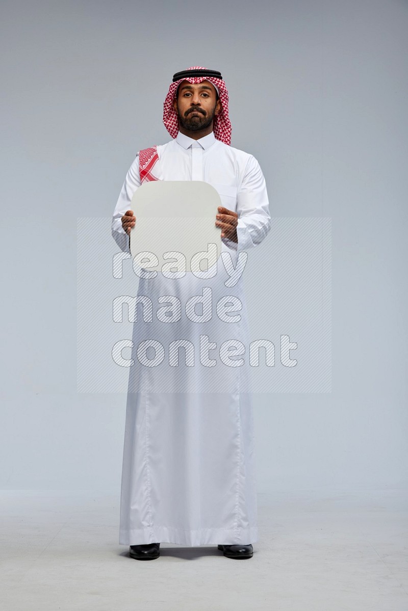 Saudi man Wearing Thob and shomag standing holding social media sign on Gray background