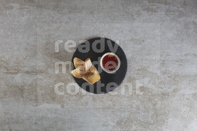 wonton cups with soy sauce ramkin on circle slate on grey textured counter top