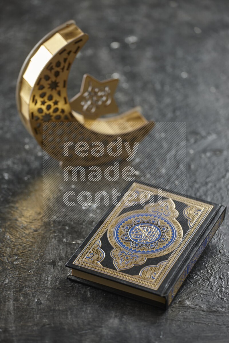 A wooden golden crescent lantern with different drinks, dates, nuts, prayer beads and quran on textured black background