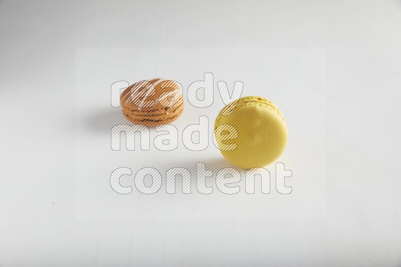 45º Shot of of two assorted Brown Irish Cream, and Yellow Lemon macarons on white background