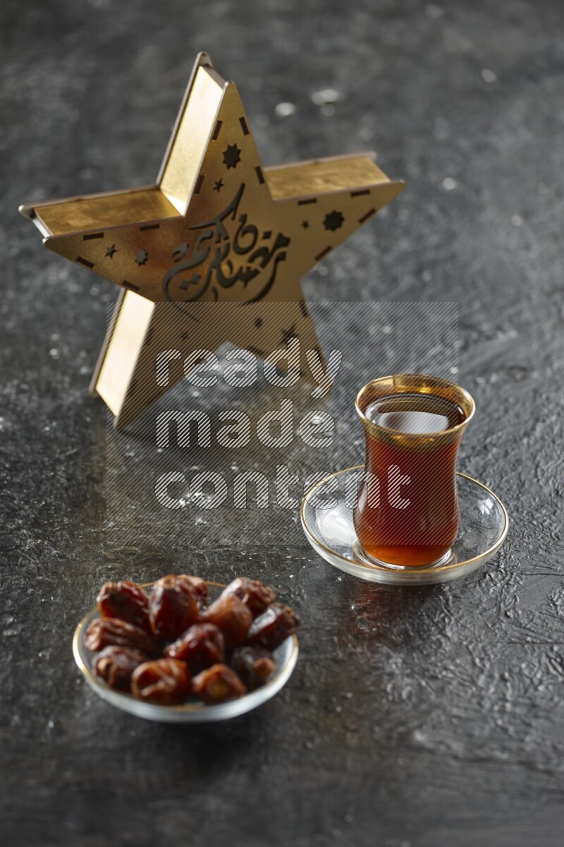 A wooden golden star lantern with different drinks, dates, nuts, prayer beads and quran on textured black background
