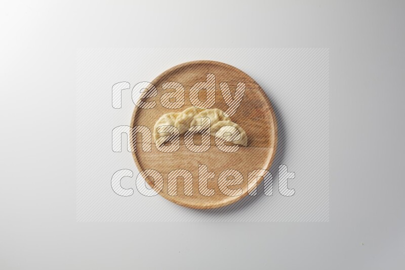 Four Sambosas on a wooden round plate on a white background