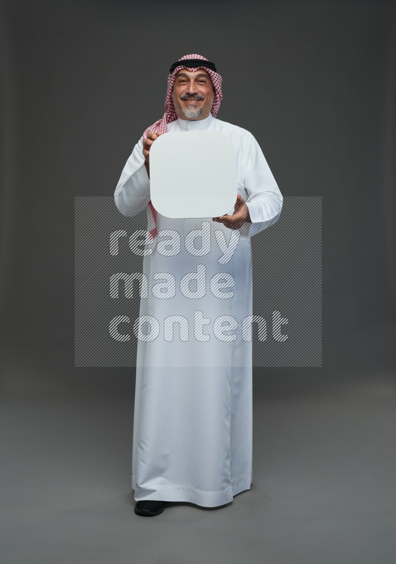 Saudi man with shomag Standing holding social media sing on gray background