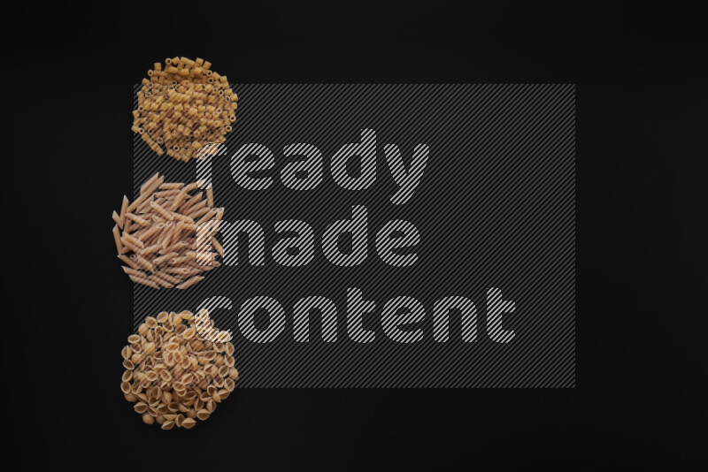 Different pasta types in 3 bunches on black background