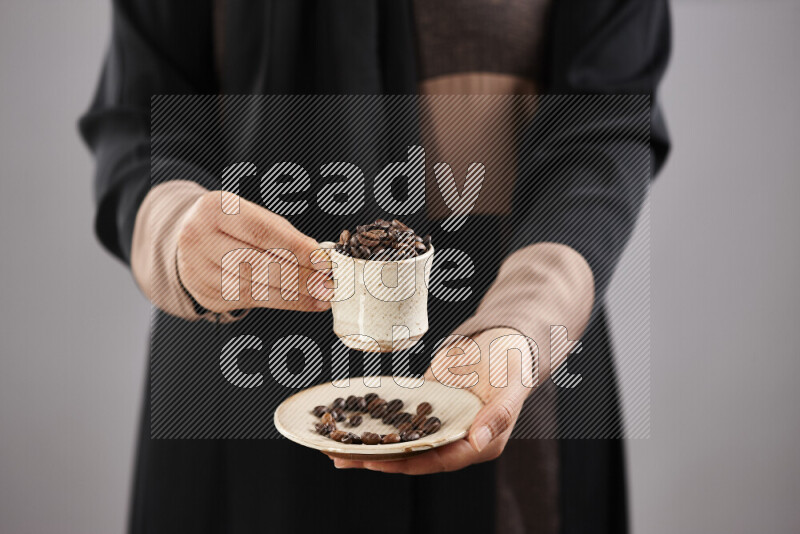 Woman in abaya holding different kinds of coffee beans in different positions