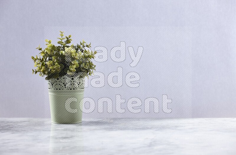Artificial plant in green decorative pot on grey marble background