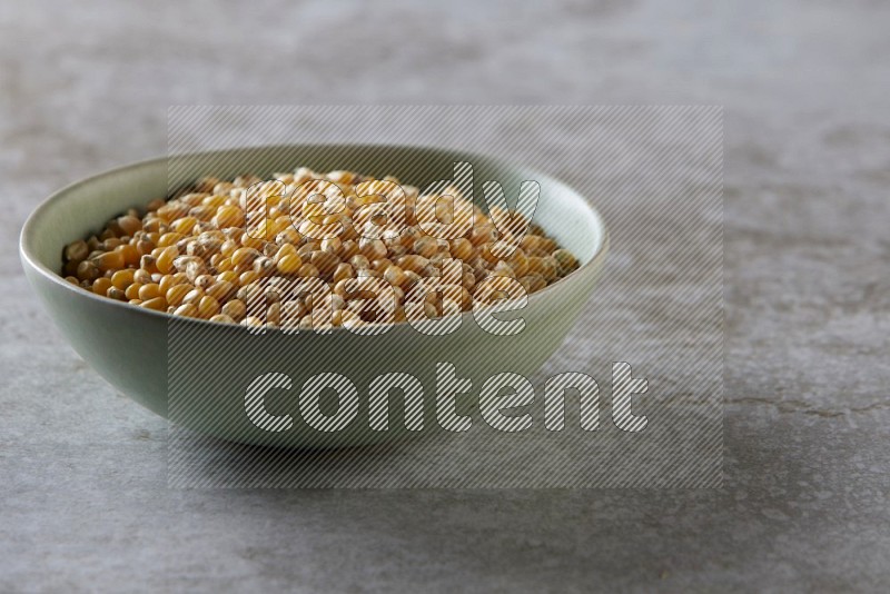 corn kernel in a green ceramic bowl on a grey textured countertop