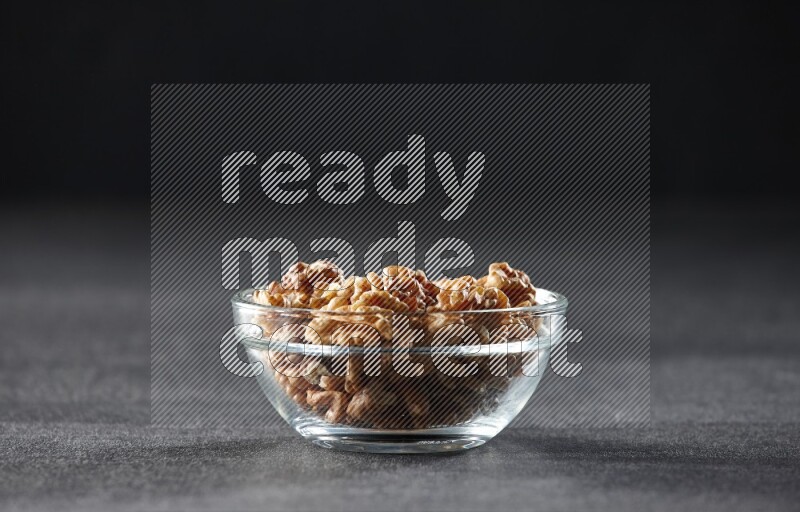 A glass bowl full of peeled walnuts on a black background in different angles