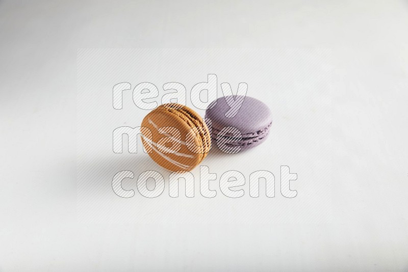 45º Shot of of two assorted Brown Irish Cream, and Purple Blueberry macarons on white background