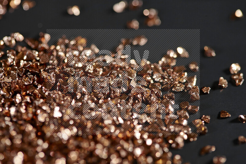 Bronze shimmering fragments of glass scattered on a black background