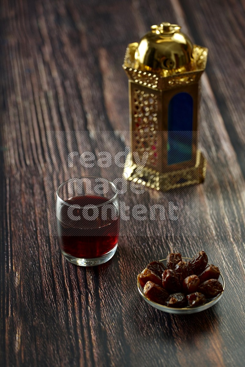 A golden lantern with drinks, dates, nuts, prayer beads and quran on brown wooden background