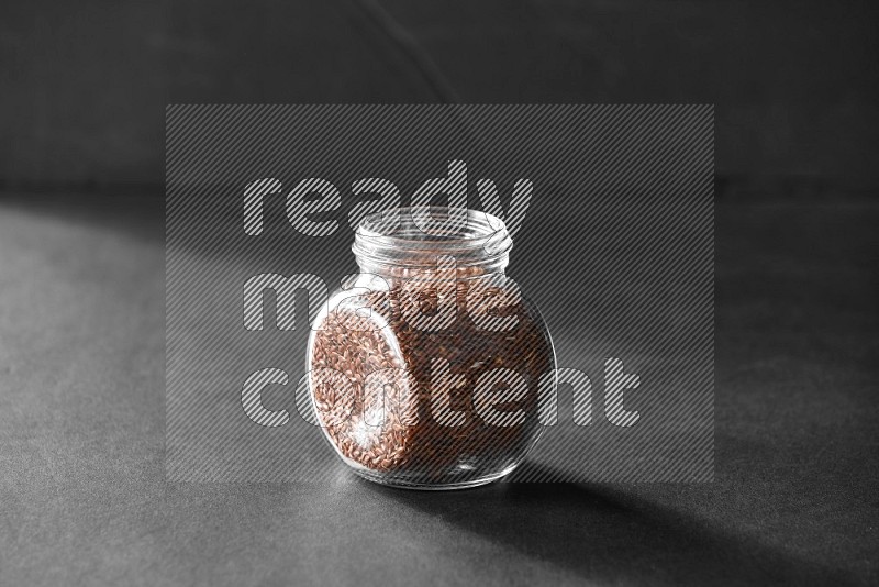 A glass spice jar full of flax on black flooring