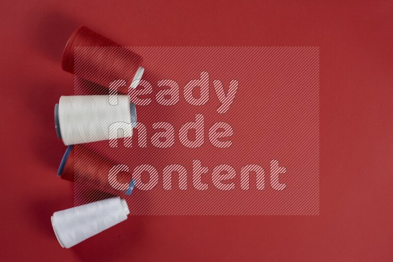 A white collection of sewing and tailoring tools arranged on a red background