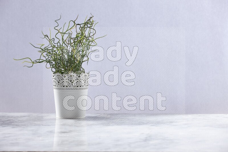 Green artificial plant in white decorative pot on grey marble background