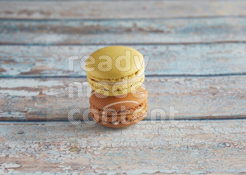 45º Shot of of two assorted Brown Irish Cream, and Yellow Lime macarons on light blue background