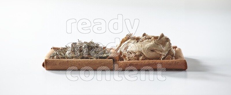 مربعان من أعواد القرفة ممتلئان بالزنجبيل المجفف والريحان المجفف علي خلفية بيضاء